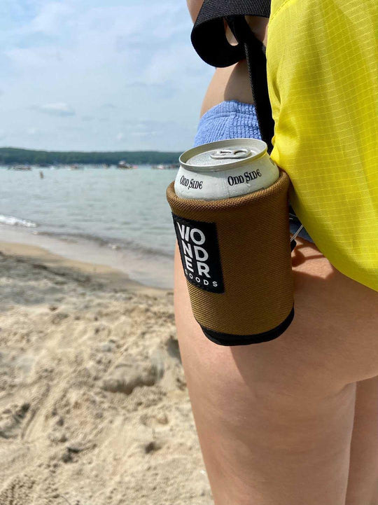 Wonder Goods beverage koozie attached to backpack strap on a Traverse City beach in Michigan.