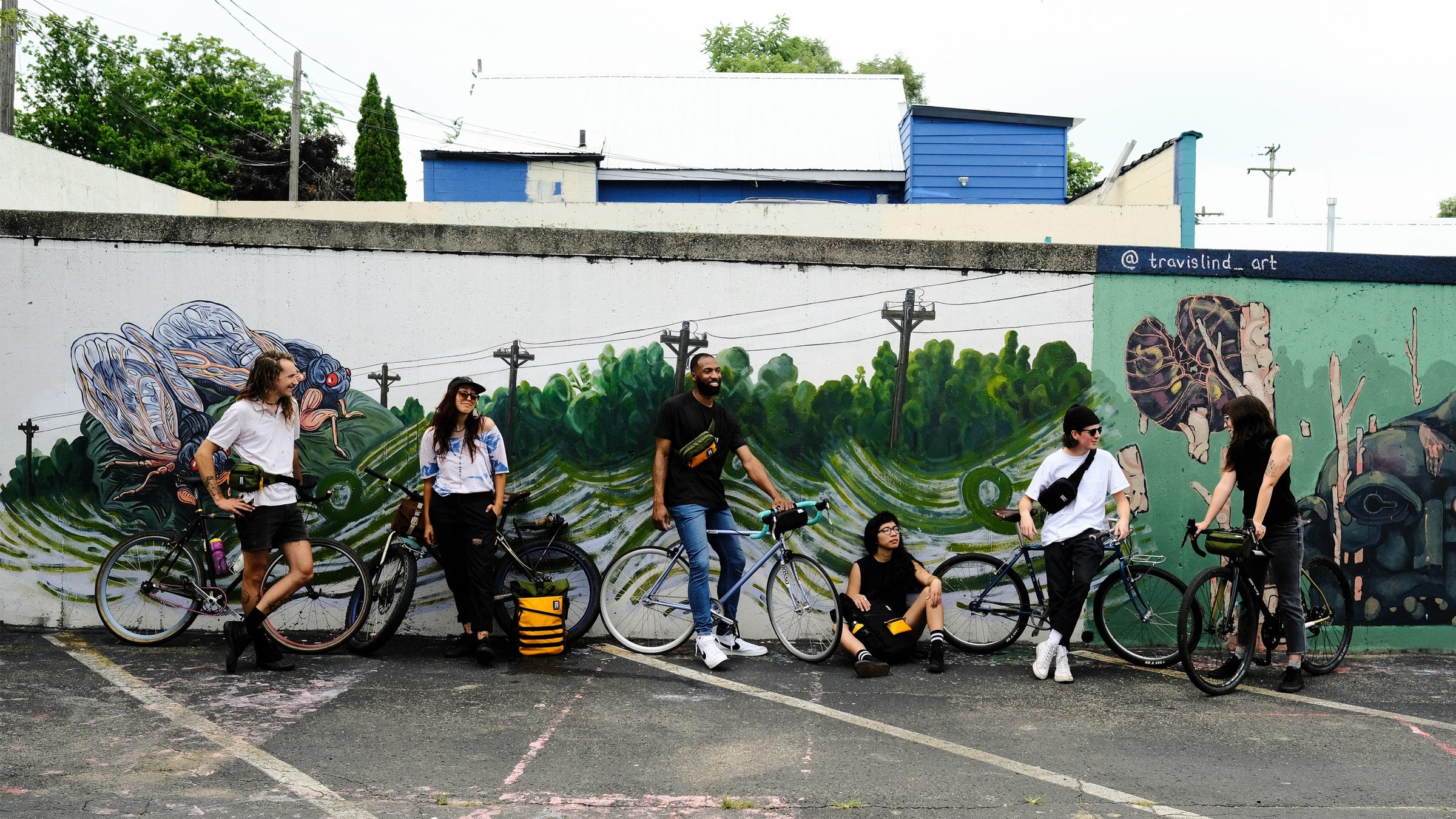 Wonder Goods crew hanging out with their bags by a mural