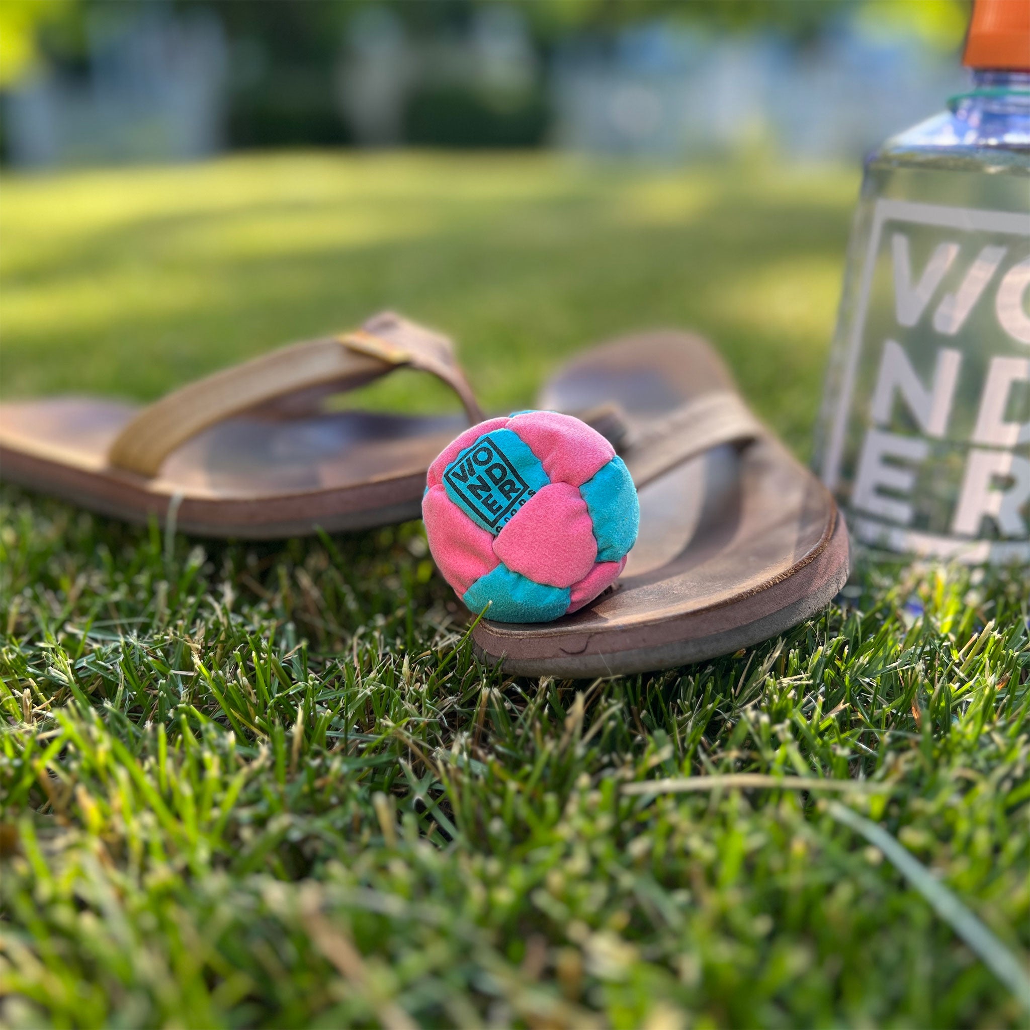 Pink and teal foot bag hacky sack on a flipflop  